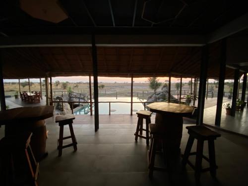 Mababe的住宿－Mababe River Campsite，餐厅设有凳子,享有游泳池的景色