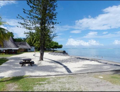 a picnic table on a beach near the water at Tuatahi Beach Lodge in Punaauia
