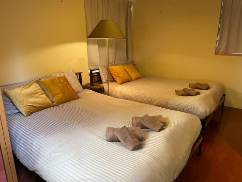 Dos camas en una habitación de hotel con toallas encima. en Petit Eturn Hakone, en Sengokuhara