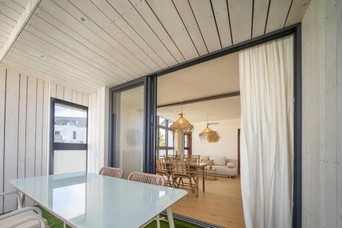 una sala da pranzo e un soggiorno con tavolo in vetro di Les Voiles - Appart'hotel "Le Kornog" a Carnac