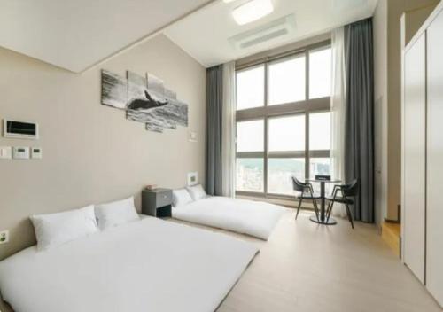 a bedroom with two beds and a desk and a window at Coopstay Yeosu Hotel in Yeosu