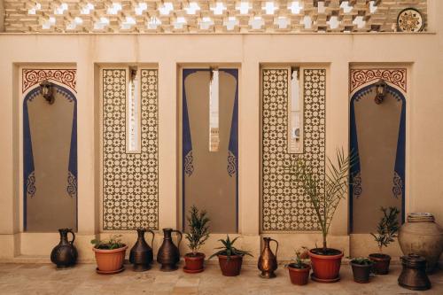 a row of vases and potted plants on a wall at Hotel SHOHRUD in Bukhara