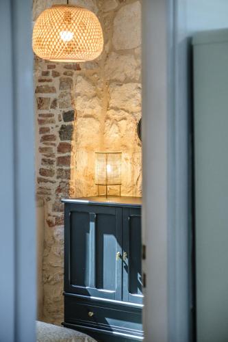 a black cabinet in a room with a stone wall at Fortuna in Nerežišće