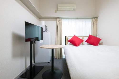 a bedroom with a bed with red pillows and a table at Palo Nagasaki in Tokyo
