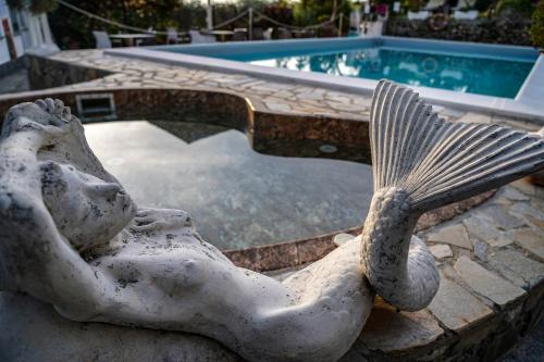 a statue of a mermaid sitting next to a pool at Hotel Bellavista in San Bartolomeo al Mare
