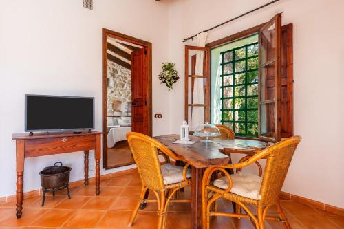 a dining room with a table and chairs and a television at Ses Solls in Petra