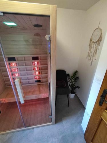 a glass door leading to a room with a chair at Sivka - mountain apartment with sauna in Kobarid