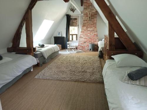 a attic bedroom with two beds and a brick wall at Maison à colombages près de Deauville, Trouville in Formentin