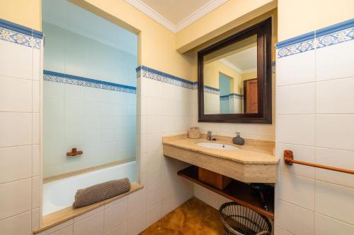 een badkamer met een wastafel, een spiegel en een bad bij Es Sostre in Petra