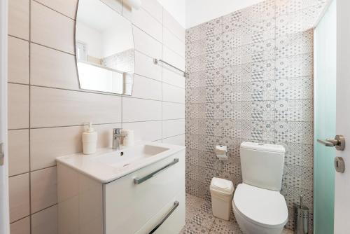 a white bathroom with a toilet and a sink at Blue Diamond Beach Villas in Paphos City