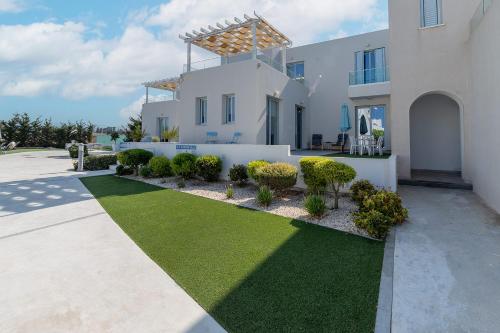 a large white house with a yard with green grass at Blue Diamond Beach Villas in Paphos City
