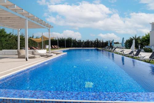 a blue swimming pool with chairs and a pavilion at Blue Diamond Beach Villas in Paphos City