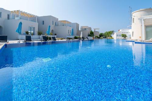 a large blue swimming pool with white buildings at Blue Diamond Beach Villas in Paphos City