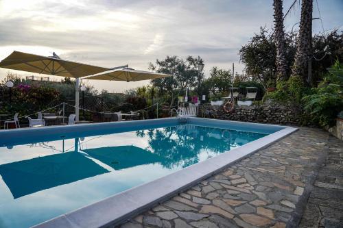 a swimming pool with an umbrella next to a house at Hotel Bellavista in San Bartolomeo al Mare