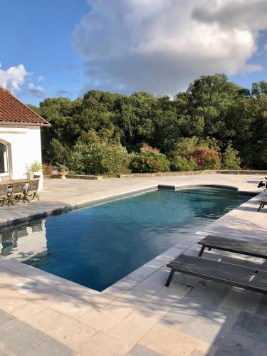 une piscine avec un banc à côté d'une maison dans l'établissement L'adret du bois, à Sames