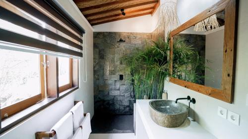 a bathroom with a sink and a stone wall at petra bianca uluwatu in Uluwatu