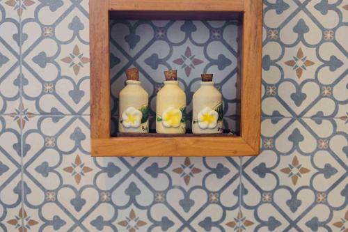three white bottles on a shelf on a wall at Om Ham Retreat and Resort in Ubud