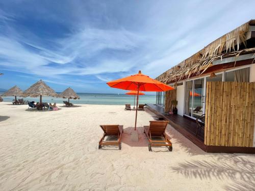 una playa con 2 sillas y una sombrilla en la arena en Nice Sea Resort, en Srithanu