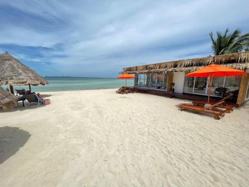 ein Gebäude am Strand mit Sonnenschirmen und dem Meer in der Unterkunft Nice Sea Resort in Srithanu