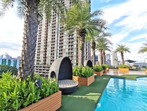una piscina de hotel con palmeras y un edificio en Capital O 75451 Podstel Hostel Bangkok, en Bangkok