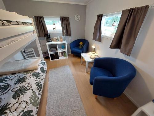 a bedroom with a blue chair and a bed and window at Guestrooms at Forest Family Home in Ytterhogdal