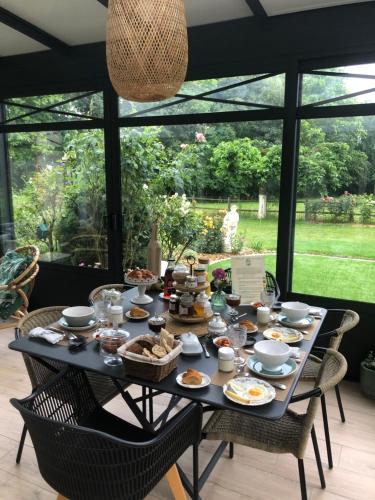 uma mesa com comida numa sala com janelas em La Grange d'Hélène em Cholet