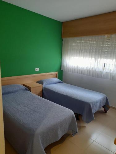 um quarto com duas camas e uma parede verde em Micampus Lugo Student Residence em Lugo