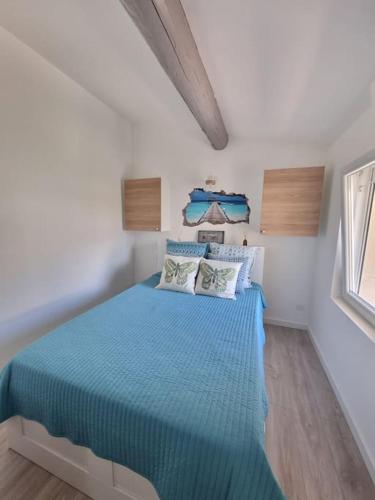 une chambre avec un lit bleu dans une pièce blanche dans l'établissement Charmante petite maison, à Le Crès