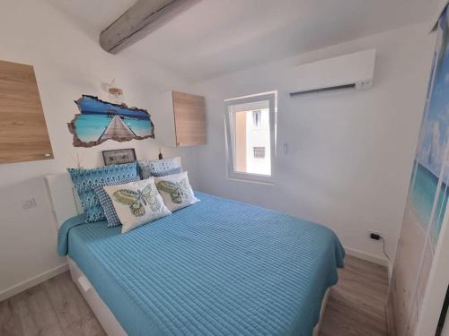 een slaapkamer met een bed met blauwe lakens en een raam bij Charmante petite maison in Le Crès