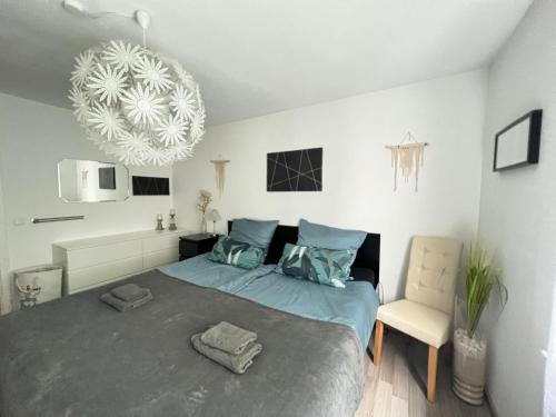 - une chambre avec un lit, une chaise et un lustre dans l'établissement Steinach-Apartment-Neuffen, à Neuffen