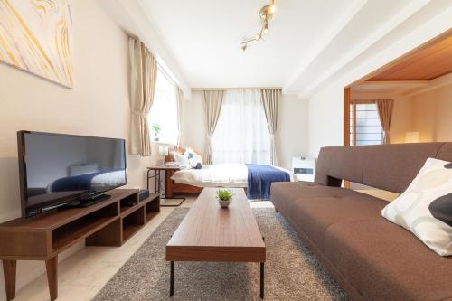 a living room with a couch and a tv and a bed at Park Residence in Sapporo