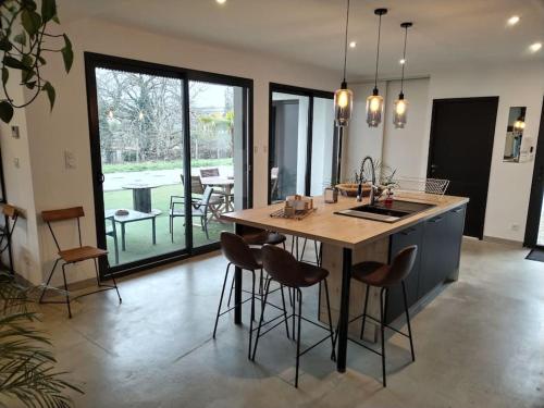 une cuisine avec un îlot doté de tabourets de bar et d'une table dans l'établissement Maison d'Architecte, à Meyssac