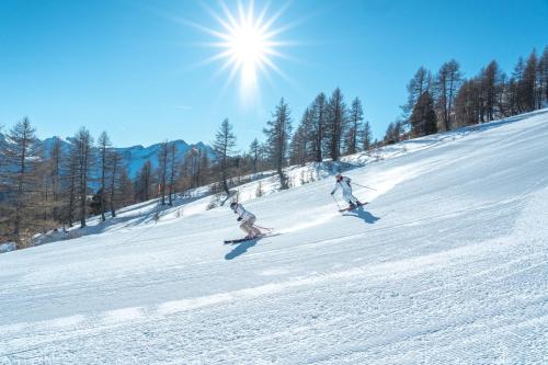 two people are skiing down a snow covered slope at SOWELL RESIDENCES Pra Loup in Pra-Loup