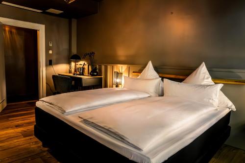 a bedroom with a large bed with white sheets and a desk at The Boutique Hotel Dsignio in Ladenburg