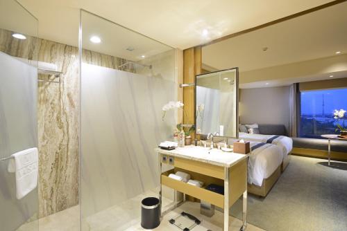 a bathroom with a bed and a sink and a shower at Vasa Hotel Surabaya in Surabaya