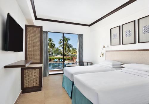a hotel room with two beds and a television at Fairfield by Marriott Goa Anjuna in Anjuna