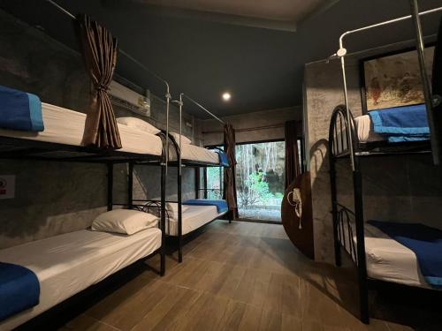 a room with three bunk beds and a window at Mountain View Party Hostel in Ban Chong Phli