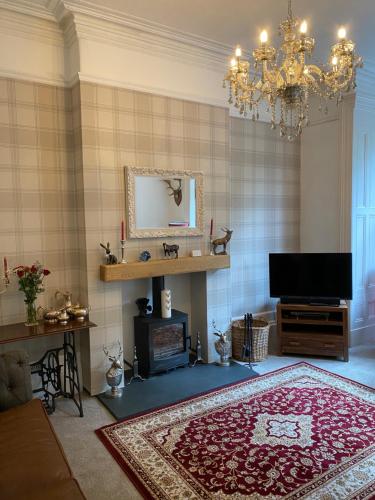 un soggiorno con lampadario pendente e tappeto rosso di Heathbank House B&B a Matlock Bank