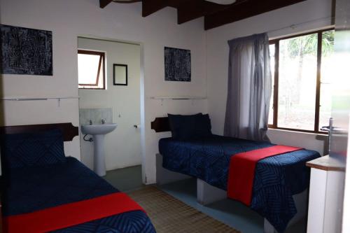 um quarto com 2 camas, um lavatório e uma janela em Whistling Woods em Empangeni