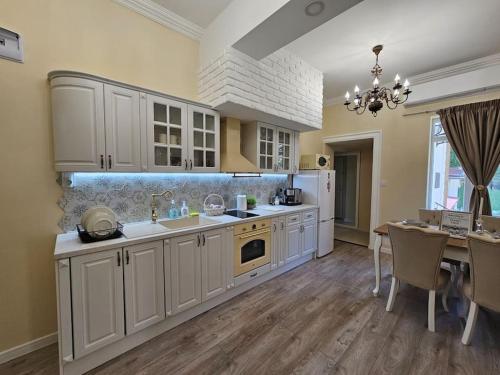 a large kitchen with white cabinets and a dining table at Iconic House Plovdiv in Plovdiv