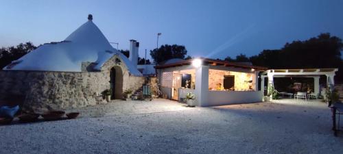 a small house with a lit up yard at night at Trullo Donna Caterina in Ceglie Messapica