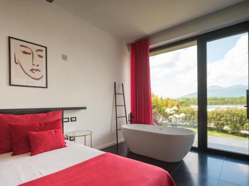 een slaapkamer met een bad en een groot raam bij Secret Garden Resort & Spa in Palma Campania