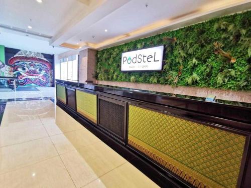 un vestíbulo de un restaurante con una pared verde en Capital O 75451 Podstel Hostel Bangkok, en Bangkok