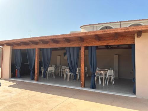 a patio with blue curtains and tables and chairs at Villa Blue Paradise Relax con piscina a pochi minuti da Cagliari e dal mare in Cagliari