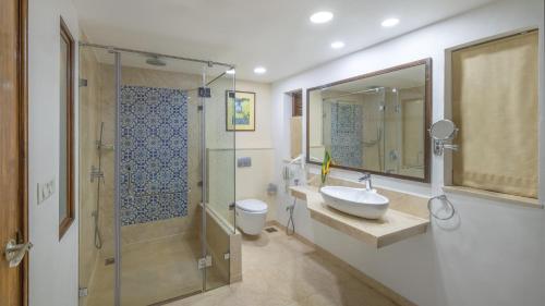 a bathroom with a sink and a shower and a toilet at Novotel Goa Dona Sylvia Resort in Cavelossim