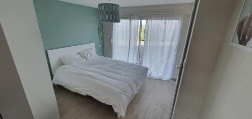 ein Schlafzimmer mit einem weißen Bett und einem Fenster in der Unterkunft Appartement au calme in Bons