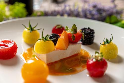 a piece of cake with fruit on a white plate at REED Boutique HOTEL & BISTRO in Siófok