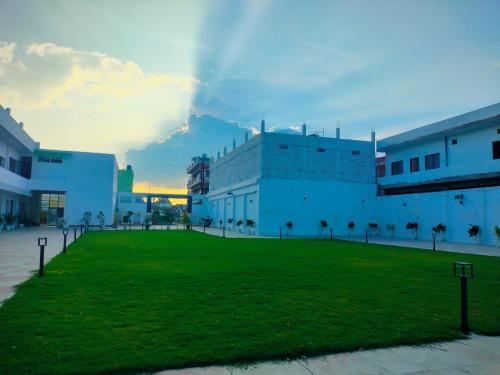 a large building with a grassy field in front of it at Hotel Buddha Park near Sarnath, Varanasi in Varanasi