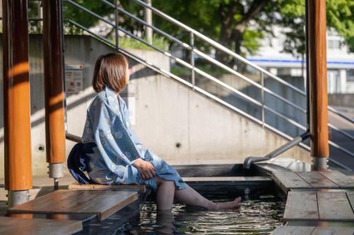 a woman sitting on the steps in water at Kamei no Yu in Yamanouchi
