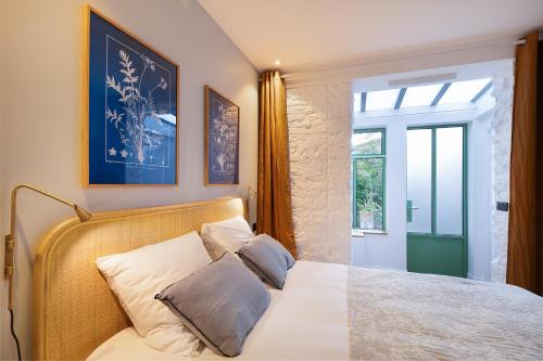 une chambre avec un lit avec des draps blancs et une fenêtre dans l'établissement Boutik Boheme L'Atelier Père Lachaise, à Paris